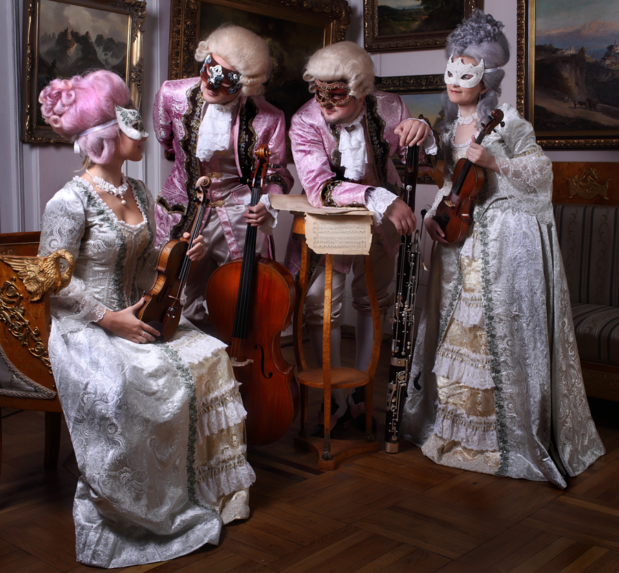 Струнный камерный оркестр в старинных костюмах эпохи барокко в венецианских масках и французких пудренных париках